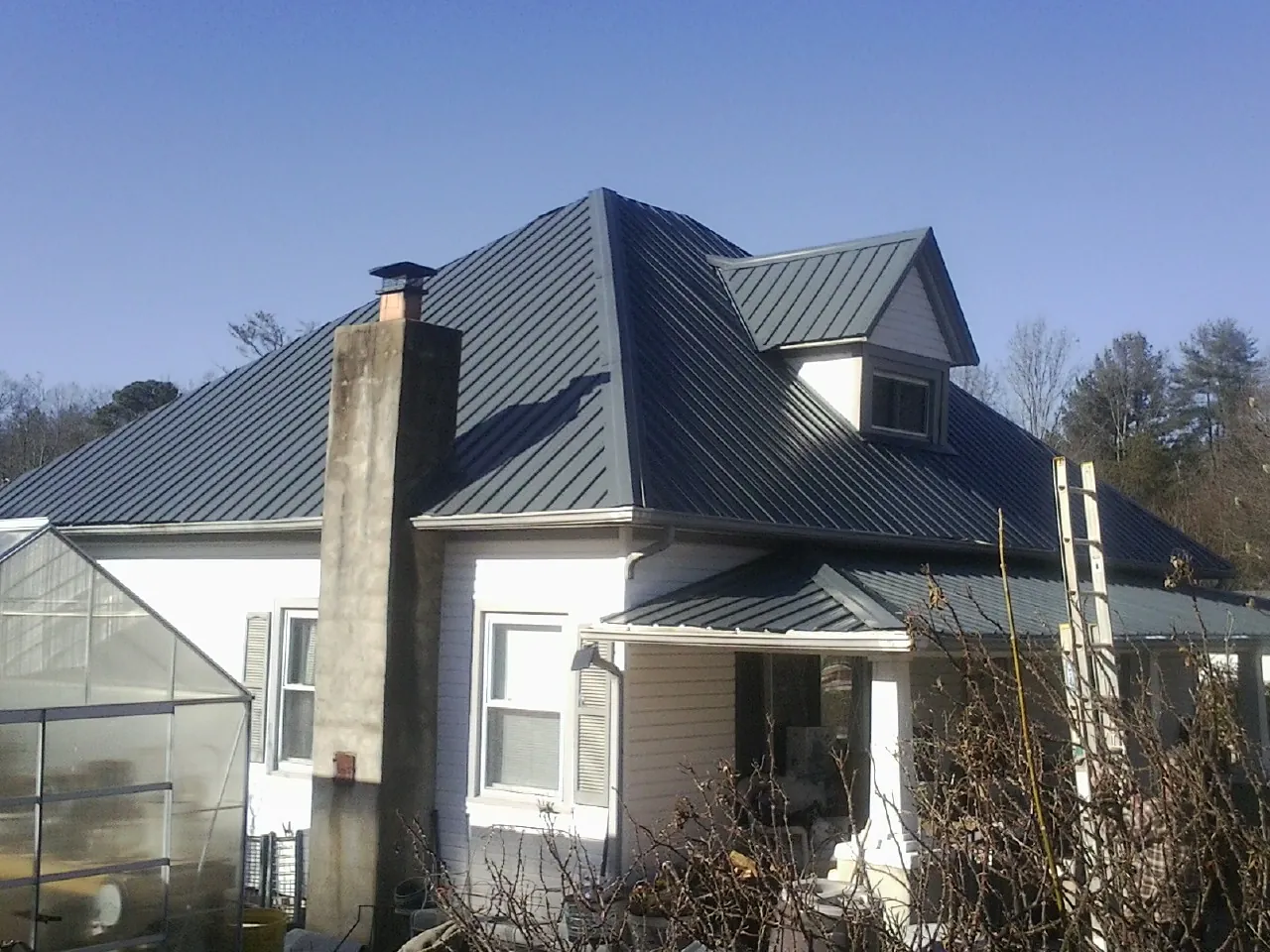 Dark blue standing seam metal roof on a white farmhouse with dormer — Slate & Tile Roof Repair by Roofing Brothers in Chester Heights