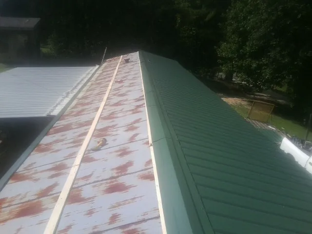 Old rusted panels beside newly installed green metal roofing — Wind Damage Roof Repair by Roofing Brothers in Chester Heights