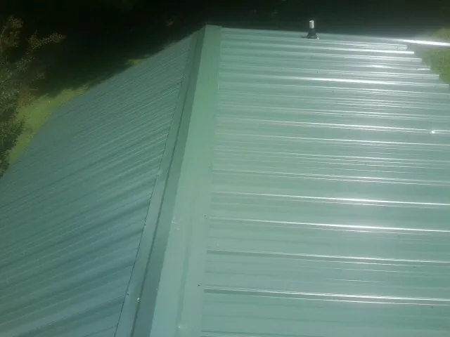 New green metal panels meeting at the ridge of a roof — Flat Roof Repair work by our crew in Chester Heights