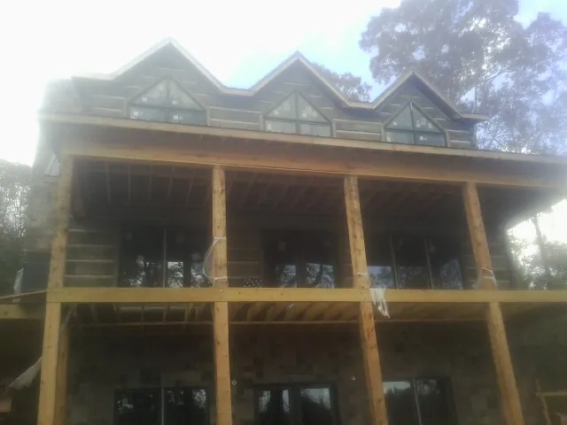 Dormers and porch framing on a large log home under construction — Roof Coating work by our crew in Chester Heights
