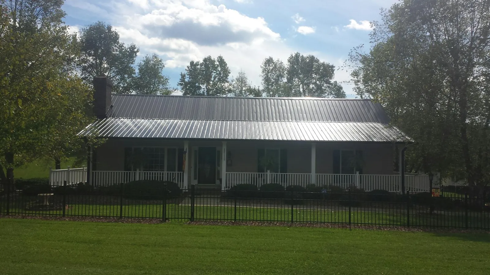 Gray metal roof on a brick ranch with a full width front porch — Gutter Guard Installation work by our crew in Chester Heights