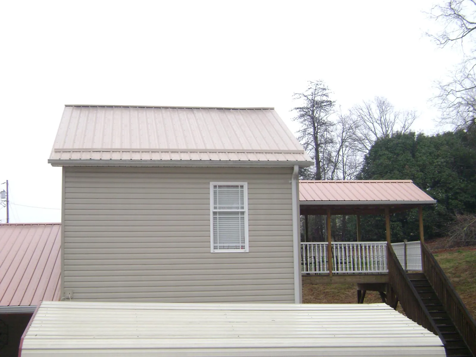 Tan metal roofs on a two story addition and attached porch, from a Roof Replacement job in Chester Heights
