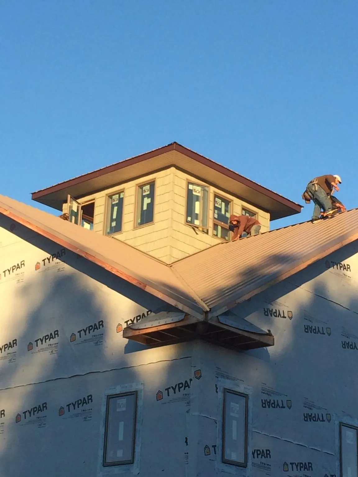 Roofers working around a rooftop cupola on a new metal roof at sunset — Roof Waterproofing in Chester Heights by Roofing Brothers